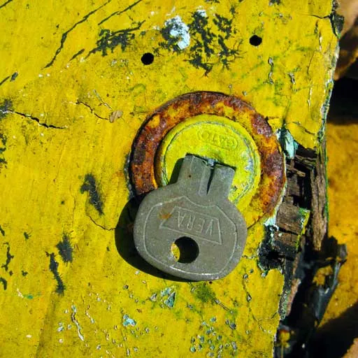 Candado metálico oxidado con la inscripción «Vera» sobre una superficie de madera pintada de amarillo y desgastada.