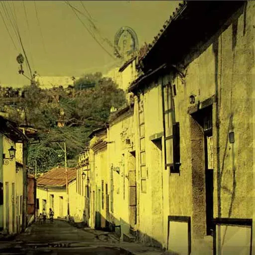 Calle de casas coloniales con fachadas amarillas y cables eléctricos, en una fotografía de tono dorado.